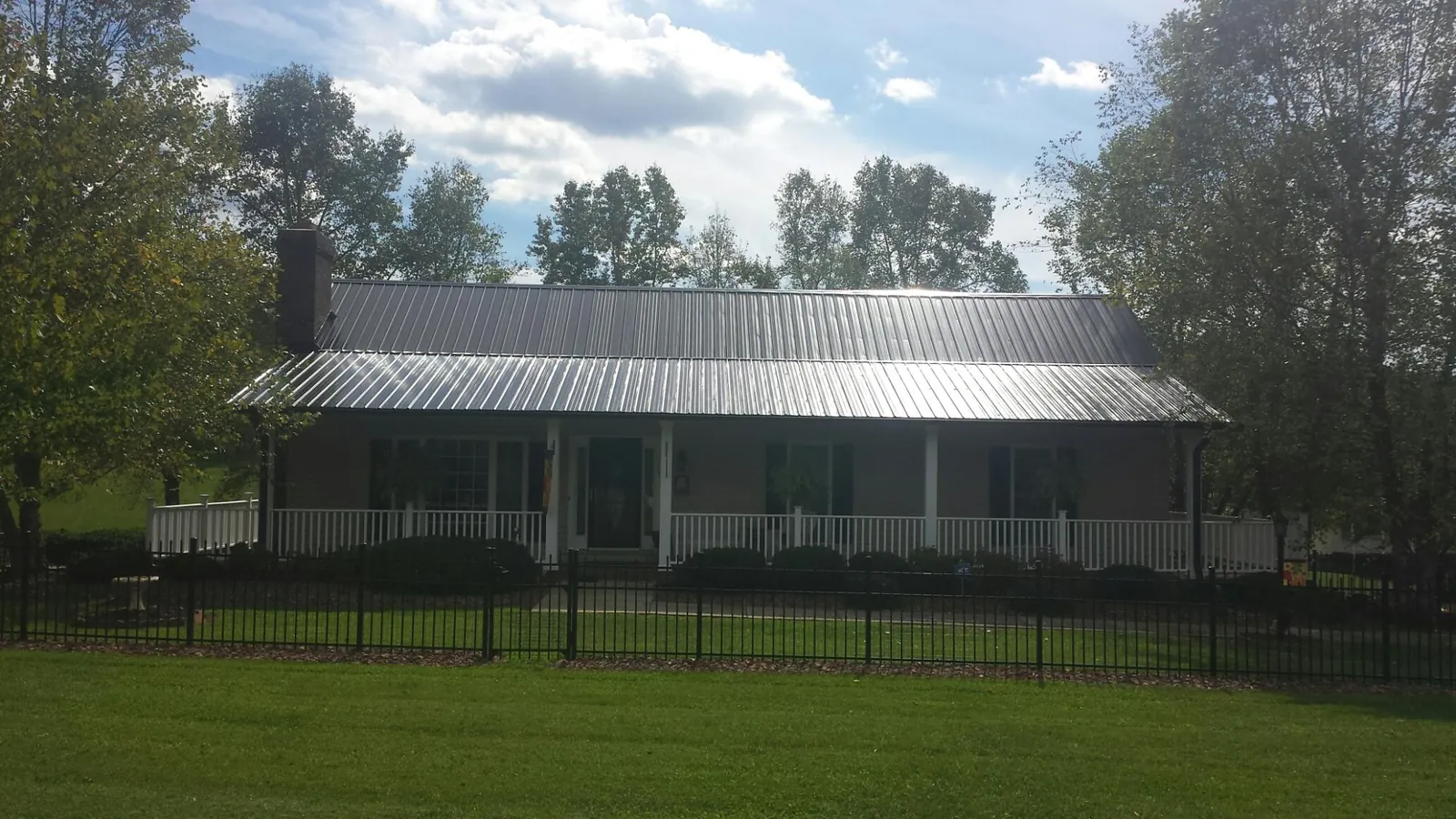 Gray metal roof on a brick ranch with a full width front porch — Gutter Guard Installation work by our crew in Lewiston