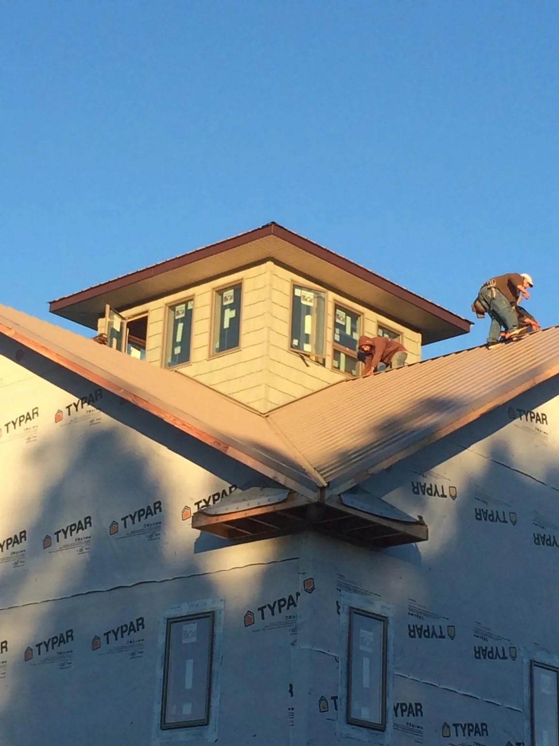Roofers working around a rooftop cupola on a new metal roof at sunset — Roof Waterproofing in Lewiston by Roofing Brothers
